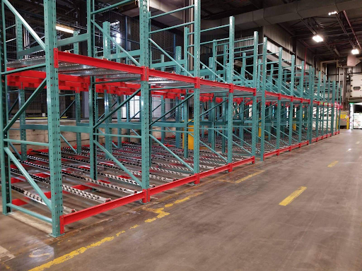 Palettier à accumulation dynamique (pallet flow) avec rails à rouleaux inclinés pour le stockage haute densité de palettes dans un entrepôt industriel.