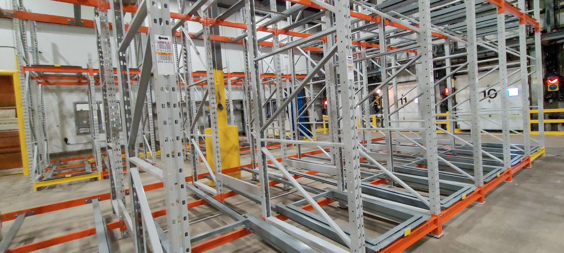 Pushback - Pedlex Heavy-duty push back rack structure with guide rails and nested carts for pallet storage in a warehouse.