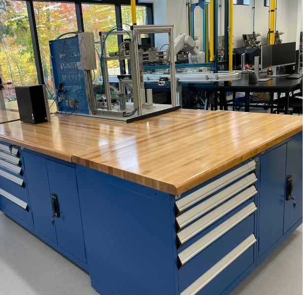 ergonomic workstation - Pedlex Industrial workstation with spacious wooden work surface and integrated blue tool cabinets with drawers for storage in a production environment.