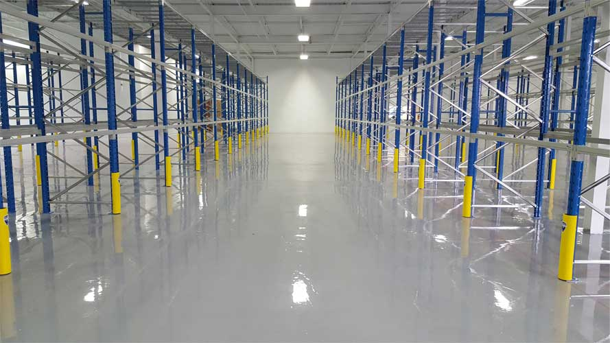 Wide industrial shelves installed in a clean, empty warehouse with yellow safety barriers, ready for high-capacity storage systems