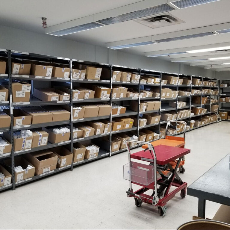 Étagères industrielles métalliques utilisées pour le rangement de boîtes et la gestion des stocks dans un entrepôt ou une salle de préparation.