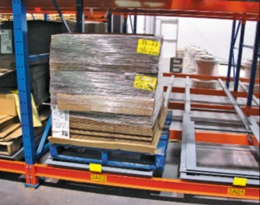 push back pallet rack - Pedlex Pallet loaded on a push back racking system in a warehouse, illustrating a gravity-fed high-density storage solution.