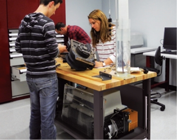 Industrial workstation with solid wood work surface used for assembly and technical training, featuring integrated mechanical components.