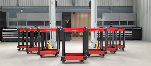 Chariots utilitaires rouges et noirs sur roulettes pivotantes, robustes et mobiles pour le transport et le rangement d’outils en atelier industriel.